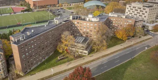 Aerial view of a building with a wave like shape on a main road with trees in the fall.