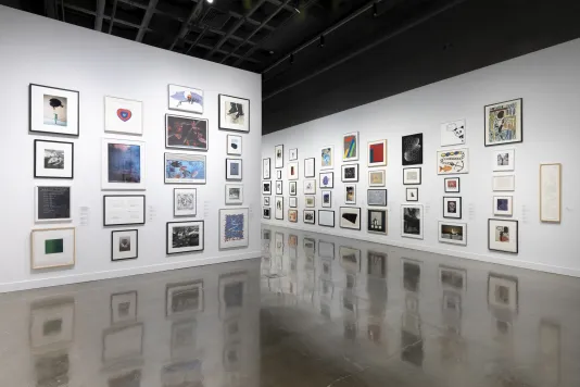 Installation view with framed artworks lining the walls floor to ceiling. 