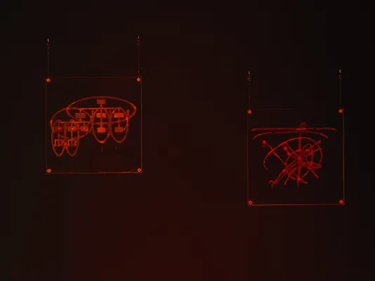  In dark room bathed in red light, two Plexiglas rectangles are suspended off-center by wire in top corners, each with CNC engraving of various overlapping ovals with diagrams. 