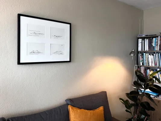A work of art mounted on the wall with a black frame and part of a bookshelf is in view on the right side.