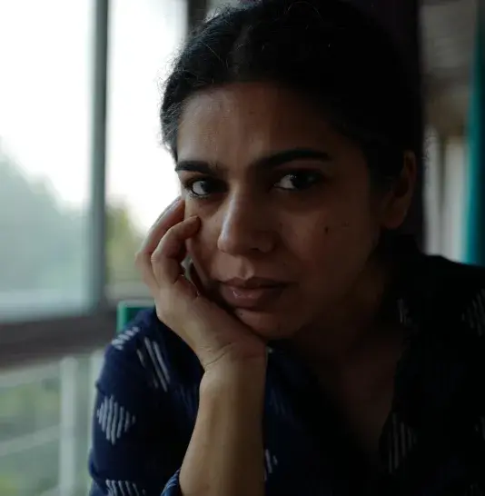 Portait of a woman with her head resting on her right hand mostly in shadow illuminated by a window on the left side.