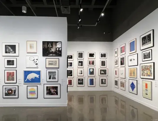 Installation view with framed artworks lining the walls floor to ceiling.