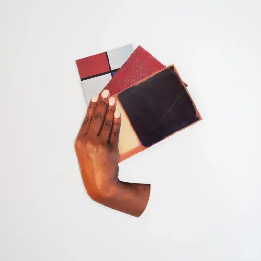 A hand holding three cards with various colors and patterns is isolated against a white background.