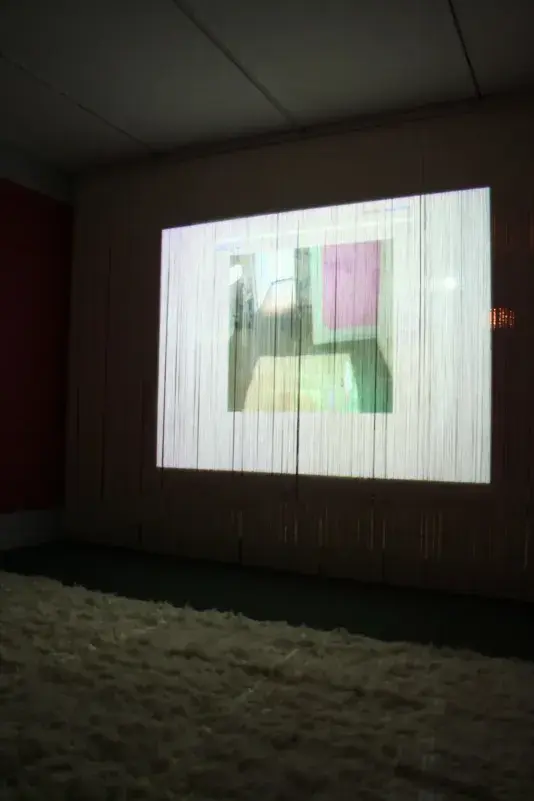 An image is projected onto a wall covered with fringe, distorting the picture. 