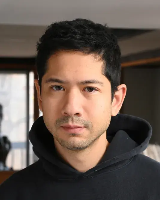 A portrait of Michael Wang, a man with a medium-light skin tone and short black hair wearing a black hoodie.