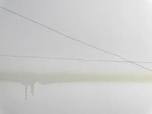 A close-up image of a white wall with lines traveling from left to right, like a comparison line graph. One line fluctuates around a consistent position, while another travels downward, intersecting the other near the image’s right edge. A more diffuse horizontal band of brown-gray color marks the wall horizontally; in one place, its lower edge bleeds down in a few darker drips.