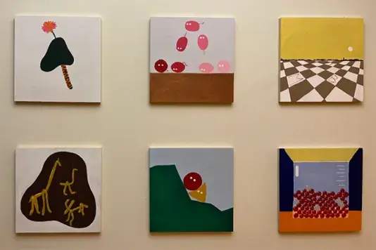 Six small square colorful paintings hung in a three column by two row grid with space in between on a beige wall.
