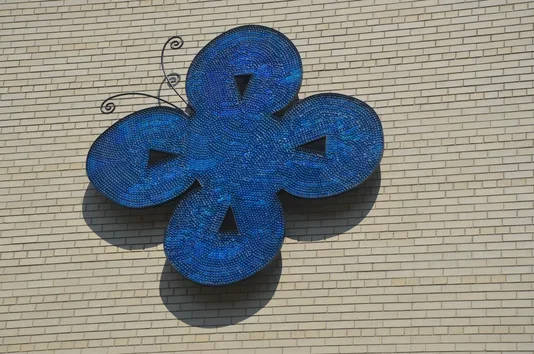 Steel butterfly mounted to a brick building wall.