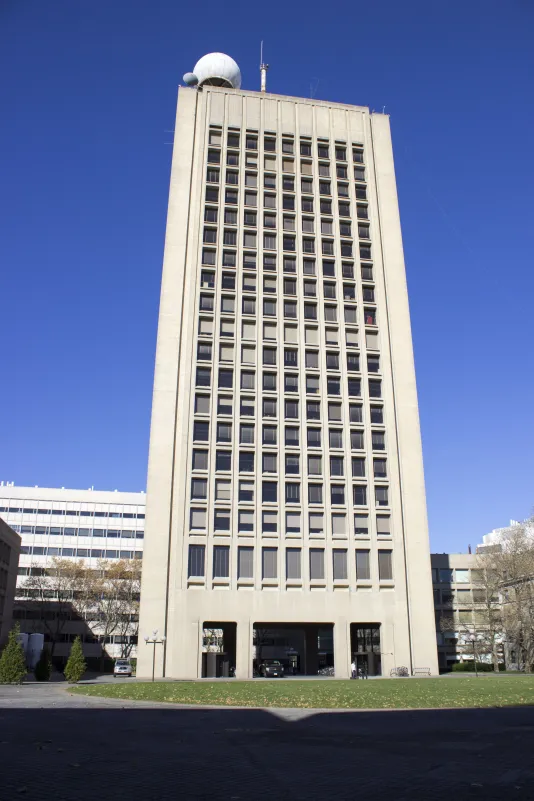 Tall grey building with many rectangular windows on each floor.
