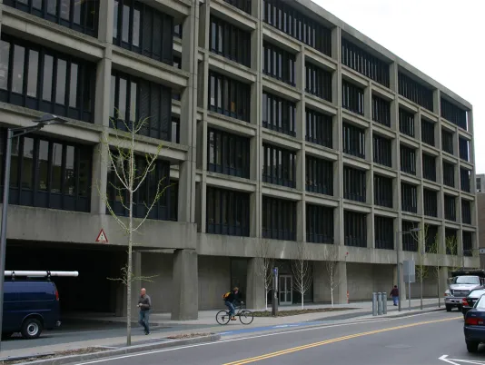 Dark grey building with windows and black frames situated on a busy street.