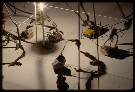 A detail photo shows motorized cars surrounded by rocks and wires. A light at the center creates deep shadows on the surface.  