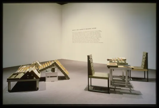 A reading area with chairs and tables made from industrial materials is set up with reading materials for viewers to look at.