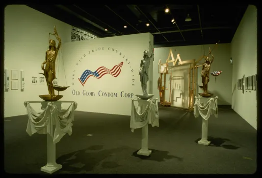 Three statues representing Justice stand in the gallery space surrounded by other hanging artworks.