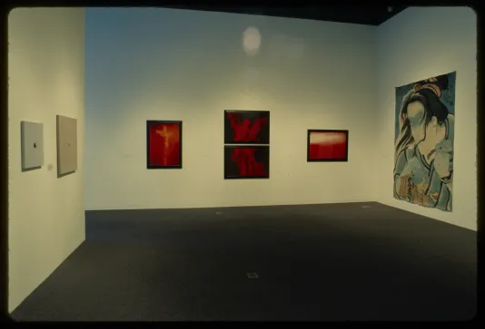 Hanging works go around the gallery walls. Three work are vibrant with red hues while the others have a delicate blue hue.