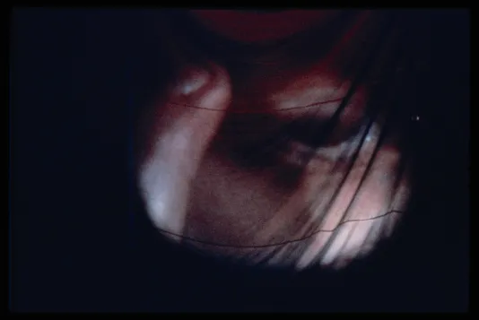 A detailed close up of a projected film. The scene looks to be a close up of a person putting a finger above their eye.