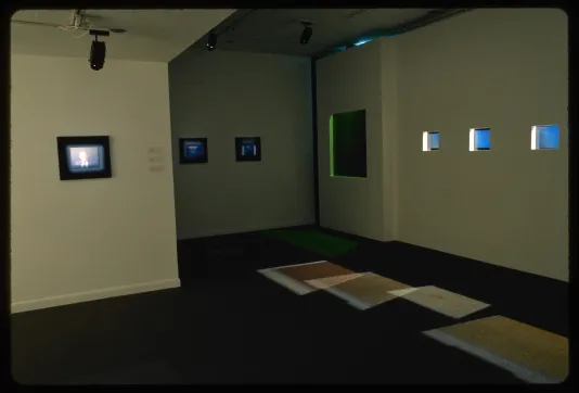 An installation shows multiple small screens embedded in the gallery wall creating holographic images. 