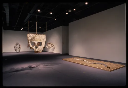 A skull hangs from the ceiling while a hand and heart sculpture sit at the opposite end. A snake sculpture lays on the floor.