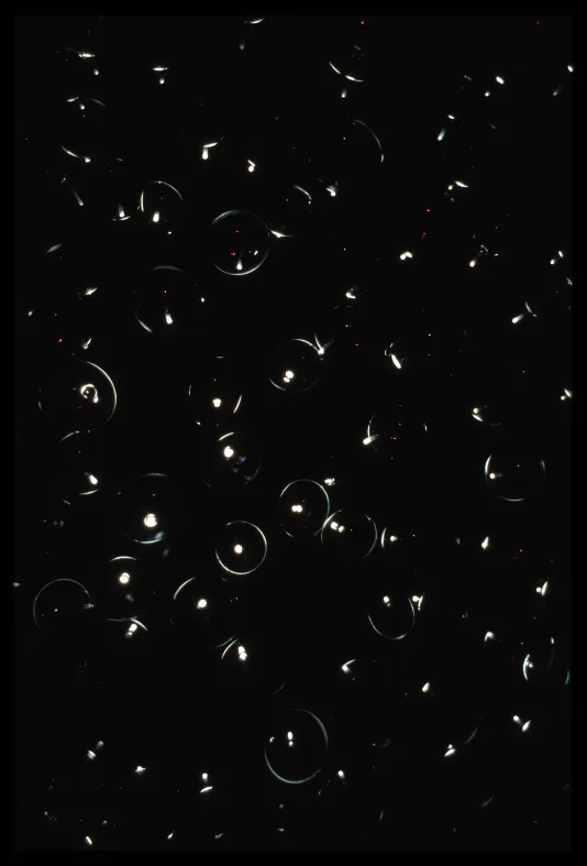 Glass bubbles appear to float in a black space.