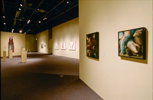 2 paintings on right gallery wall lead viewer into large space displaying paintings, drawings and sculptures on pedestals.