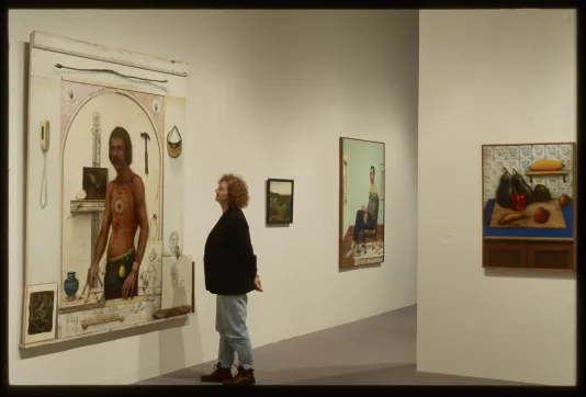 A woman gazes at a large painting of a man.
