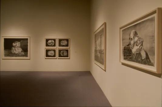 Framed, black and white drawings hang on walls in a corner of the gallery.