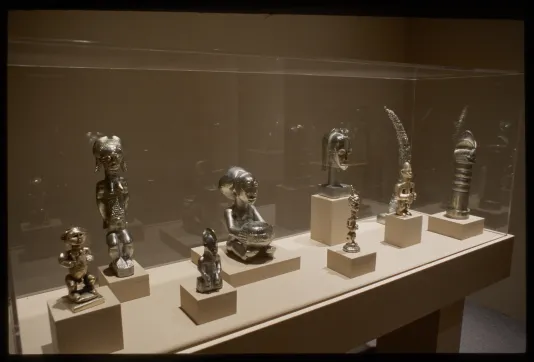 Vitrine with 8 small brass trophy-like sculptures.
