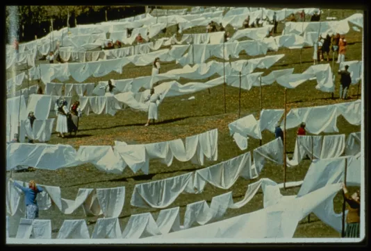 Row upon row of clotheslines, all hung with white linen, are tended to by villagers.