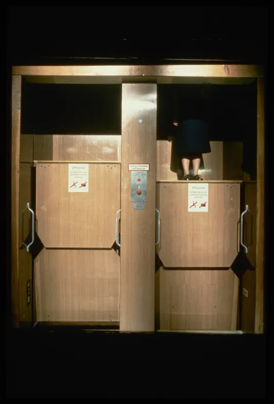The lower half of a woman is visiblw while riding in a lift.