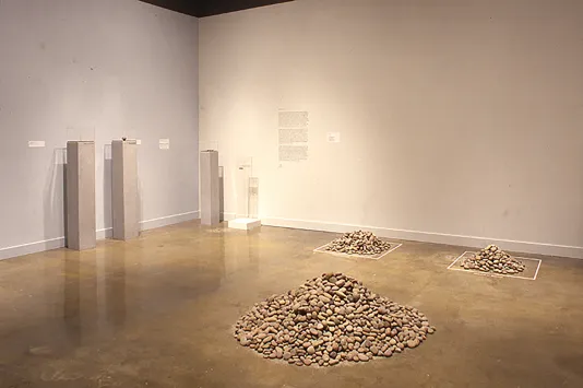 Three piles of sand colored stone lie opposite thin gray pedestals