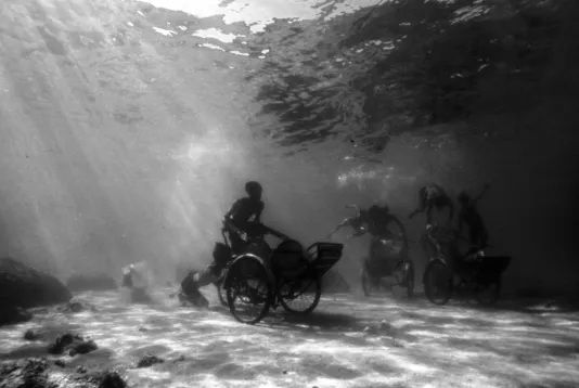 Black and white still featuring cyclo drivers pushing empty rickshaws on the ocean floor