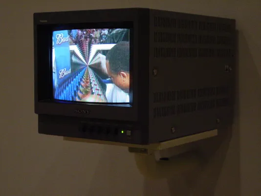 Box television monitor is mounted to the wall; it’s screen shows a colorful image warped and twisted