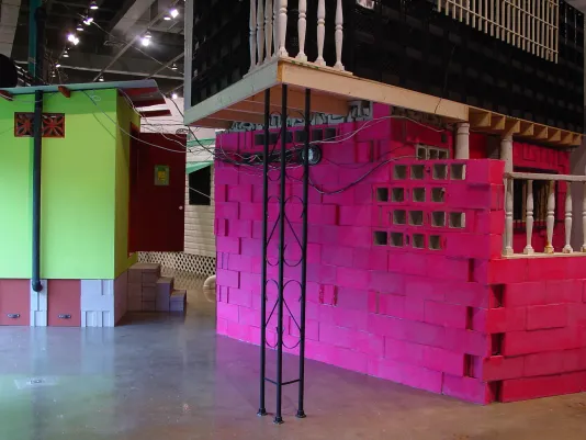 A zoomed in look at a structure built with pink painted blocks and a smaller structure painted bright green in the background