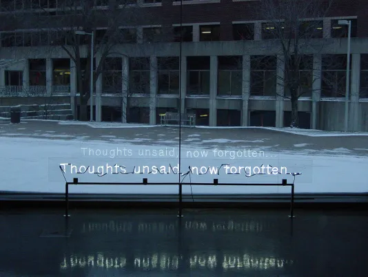 Neon light artwork installed in front of a window, its reflected text appears like a caption for the snowy view outdoors.