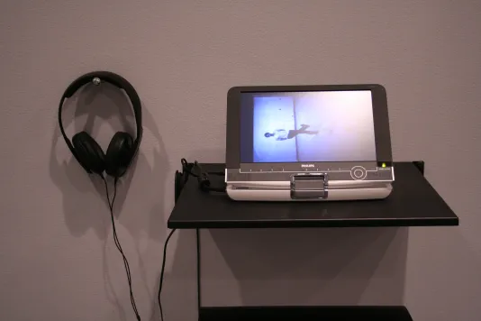 One small TV with headphones installed in a gallery. 