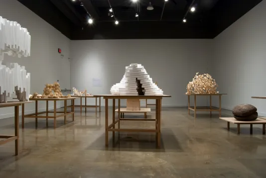 Gallery filled with Styrofoam™ block and wood sculptures on wooden pedestals
