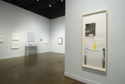 Installation view of the List Center gallery. In the foreground is a framed collage of a chair with a yellow vase and and a black and white photograph. 