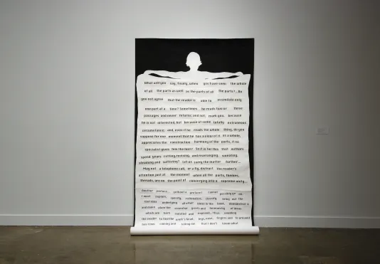 A large unfurling paper has the silouette of a woman holding a scroll style paper which contains text that appears to be cut out from a magazine.