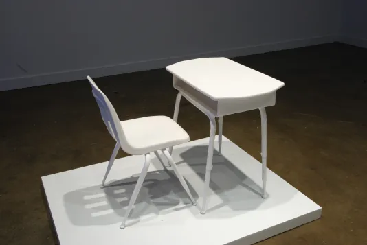 White platform with a chalk chair and desk modeled after school desks and chairs from The Bahamas