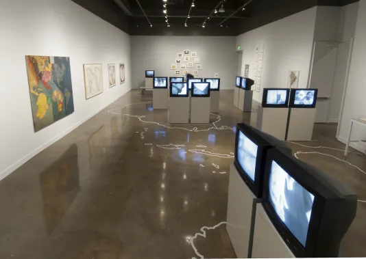 Large photo of the entire gallery showing many TV monitors with drawings on the floor.