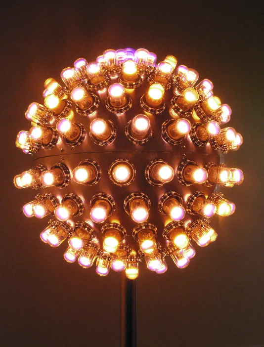Up close photo of a round sculpture lit up with many lights.