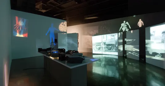Image of the installation including a table with projectors and images on the far wall