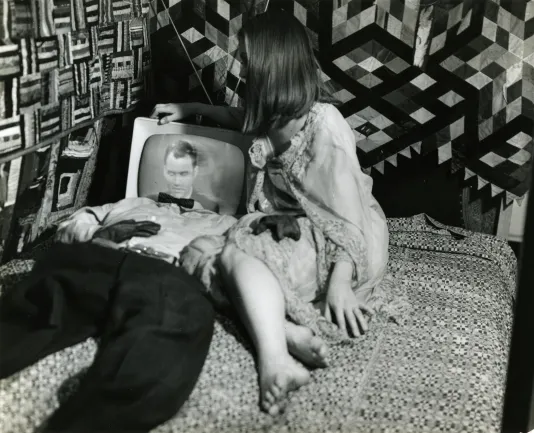 Image of a couple lying on a bed with the man’s head as a TV