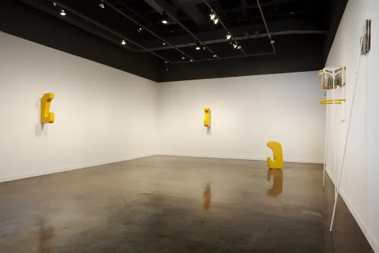 Wide shot of a gallery space displaying 3 cast aluminum sculptures, and 2 mop sculptures on the wall to the right.