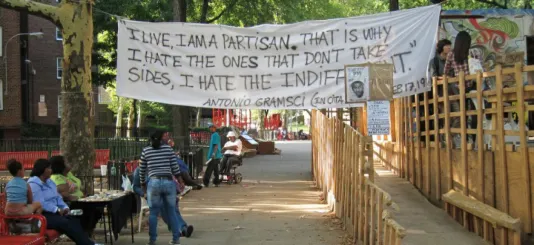 A white fabric banner hanging reads &quot;I live, I am a partisan, that is why I hate the ones that don't take sides. I hate the indifferent. Antonia Gramsci&quot;