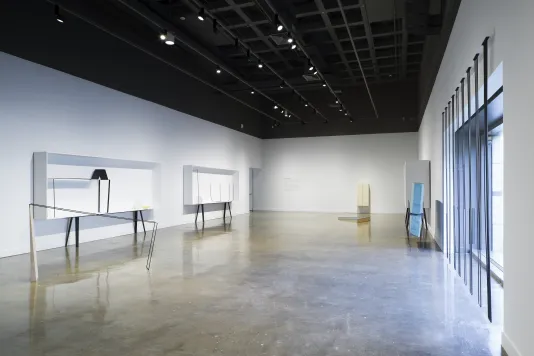 Standing and mounted sculptures and display cases fill the gallery, including a sculpture across a picture window.