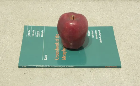 An apple sits on top of a copy of Kant's "Groundwork of the Metaphysics of Morals"