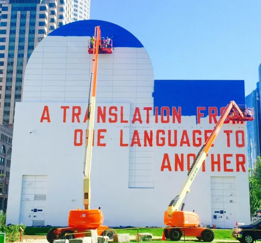 2 bucket cranes in front of the building during the painting of “A Translation From One Language To Another”.
