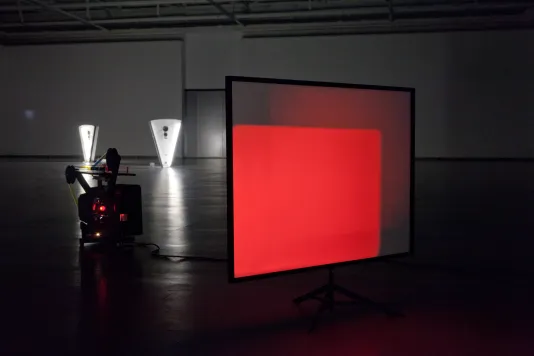 Set on the floor of a gallery, a projector cast red rectangles onto a translucent screen.