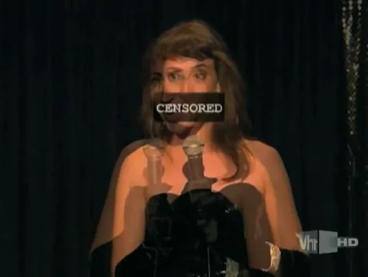 Blurred image of a young woman in formal dress holding a mic with “CENSORED” covering her mouth.