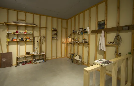 An open space with wood framing, shelves, and various found objects lining the walls